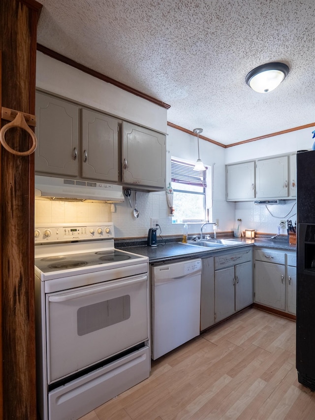 kitchen featuring crown molding, dark countertops, a sink, white appliances, and under cabinet range hood