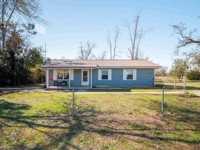 view of front of property with metal roof, a front lawn, and fence