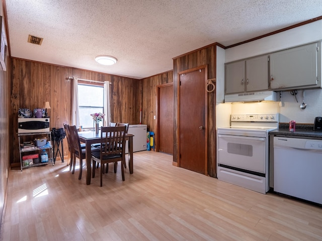 dining area with visible vents, wooden walls, light wood finished floors, and a textured ceiling