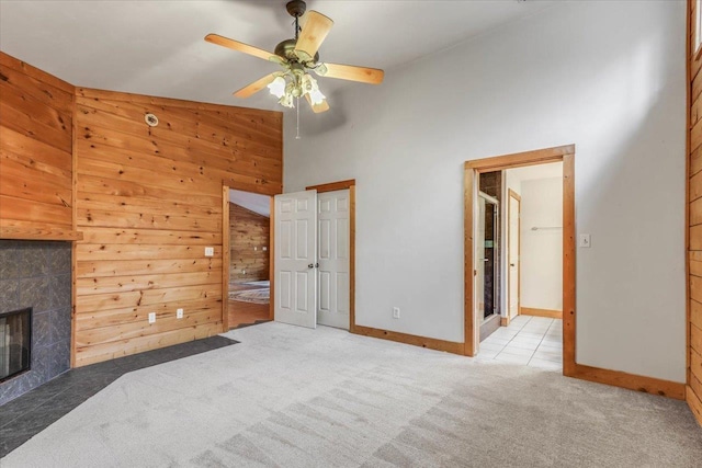 220 Deer Pass, Havana, FL 32333 - unfurnished bedroom featuring wood walls, baseboards, a high ceiling, a tiled fireplace, and carpet