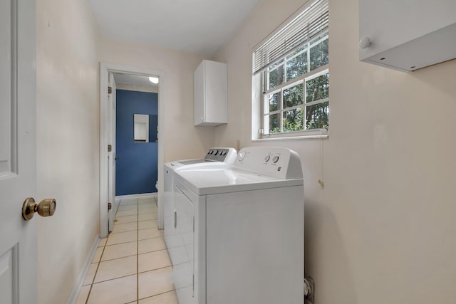 clothes washing area featuring cabinets, washer and clothes dryer, and light tile patterned flooring