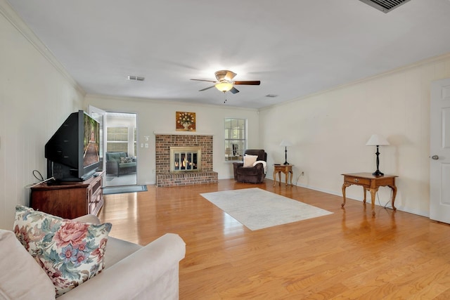 living room with light hardwood / wood-style floors, a brick fireplace, a wealth of natural light, and crown molding