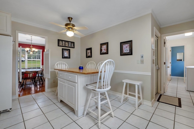 kitchen featuring a breakfast bar, white fridge, white cabinetry, and ornamental molding