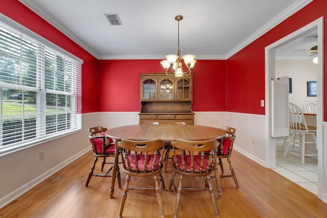 dining room with light hardwood / wood-style floors, ceiling fan with notable chandelier, and ornamental molding