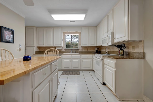 kitchen featuring white appliances, wooden counters, sink, light tile patterned floors, and white cabinetry