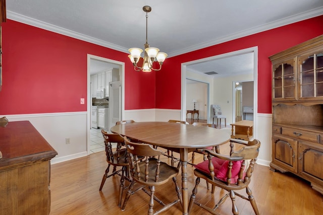 dining space featuring a chandelier, crown molding, and light hardwood / wood-style flooring