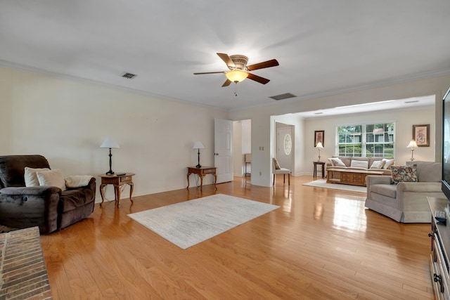 living room with crown molding, ceiling fan, and light wood-type flooring