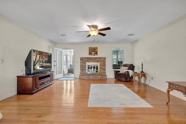 living room featuring a fireplace, ceiling fan, light wood-type flooring, and crown molding