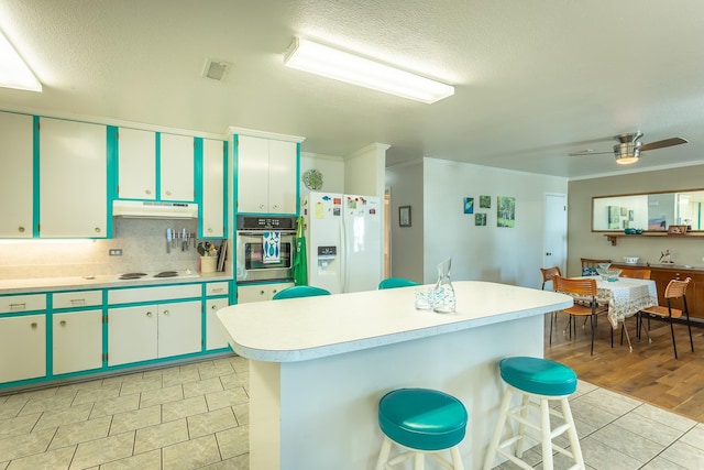 kitchen with light wood-type flooring, backsplash, white appliances, ceiling fan, and crown molding