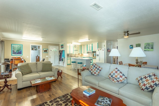 living room featuring a textured ceiling, light hardwood / wood-style floors, and ceiling fan