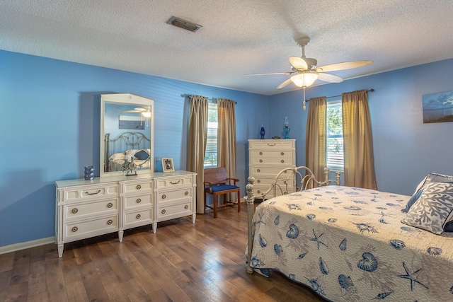 bedroom featuring a textured ceiling, ceiling fan, dark wood-type flooring, and multiple windows