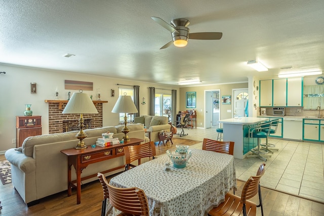 dining space featuring a textured ceiling, ceiling fan, light wood-type flooring, and sink