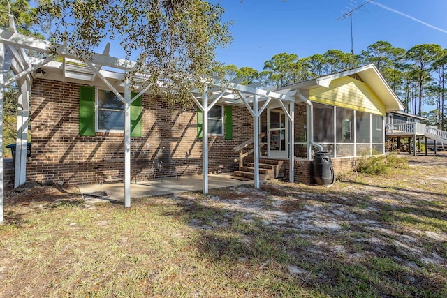 back of house with a pergola, a patio area, and a sunroom