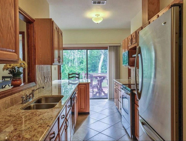 kitchen featuring appliances with stainless steel finishes, tasteful backsplash, sink, light tile patterned floors, and light stone counters