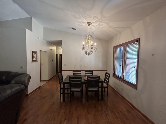 dining area with dark hardwood / wood-style flooring, a chandelier, and vaulted ceiling