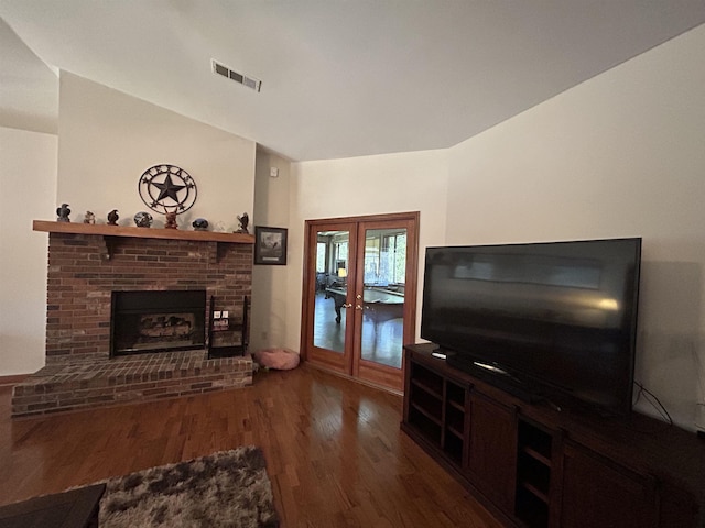 living room with a brick fireplace, dark wood-type flooring, and french doors