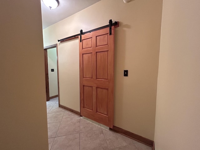 hall with light tile patterned floors and a barn door