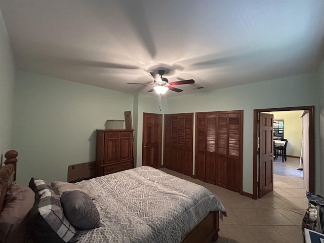 bedroom with multiple closets, ceiling fan, and light tile patterned flooring