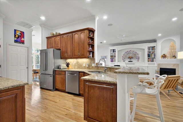 4664 Fledgling Dr, Tallahassee, FL 32311 - kitchen featuring a sink, stainless steel appliances, a peninsula, light stone counters, and a kitchen bar