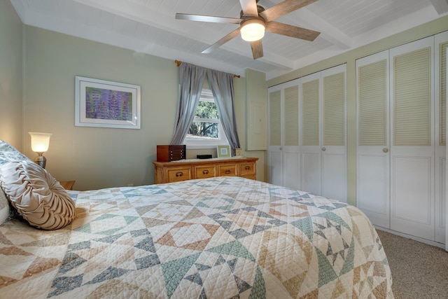 carpeted bedroom featuring multiple closets, ceiling fan, beam ceiling, and wooden ceiling