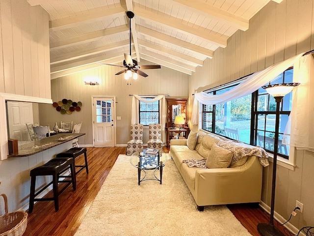 living room featuring ceiling fan, wooden walls, lofted ceiling with beams, and hardwood / wood-style floors