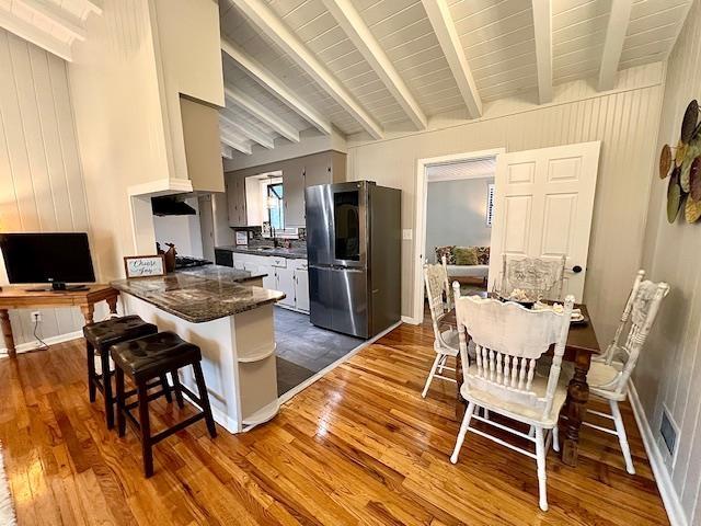 kitchen with sink, hardwood / wood-style flooring, stainless steel fridge, lofted ceiling with beams, and kitchen peninsula