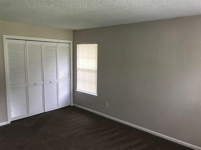 2247 Shady Timbers Cir Unit C, Tallahassee, FL 32304 - unfurnished bedroom with dark carpet, a closet, and a textured ceiling