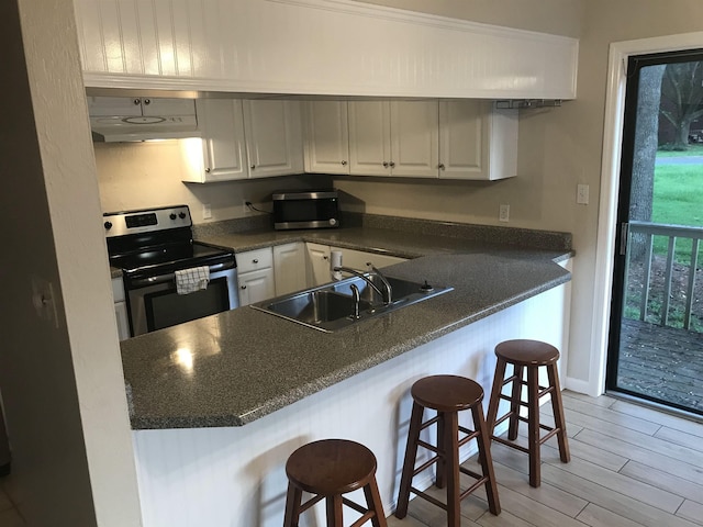 2247 Shady Timbers Cir Unit C, Tallahassee, FL 32304 - kitchen featuring appliances with stainless steel finishes, dark countertops, under cabinet range hood, a kitchen breakfast bar, and white cabinetry