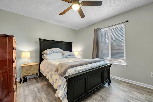 bedroom featuring ceiling fan, hardwood / wood-style floors, and a textured ceiling