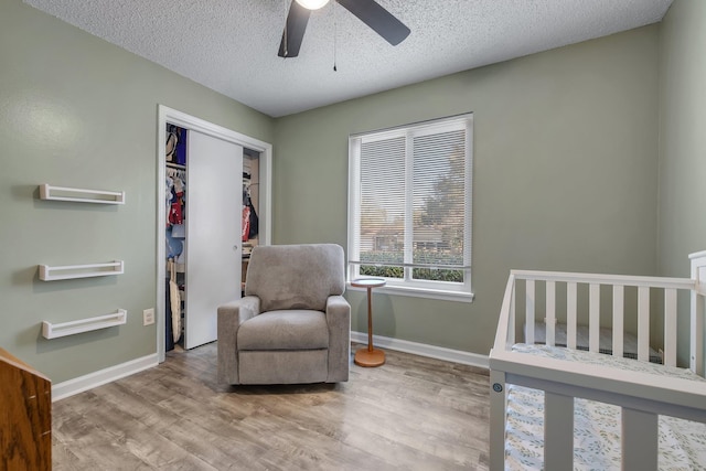 bedroom with a textured ceiling, light hardwood / wood-style floors, a closet, and ceiling fan