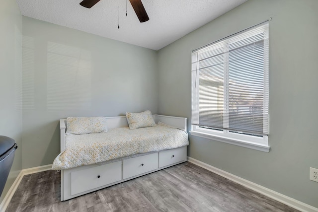 bedroom with ceiling fan, light hardwood / wood-style flooring, and a textured ceiling