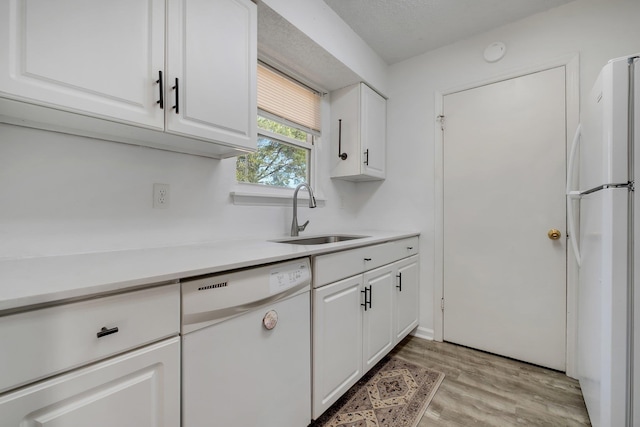 kitchen with sink, white cabinets, white appliances, and light wood-type flooring