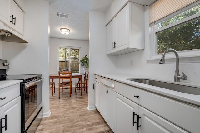 kitchen with dishwasher, sink, white cabinets, electric range, and light hardwood / wood-style floors