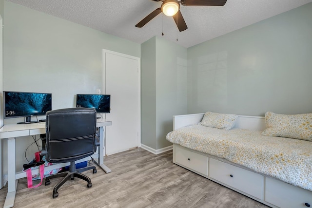 bedroom with a textured ceiling, ceiling fan, and light hardwood / wood-style flooring