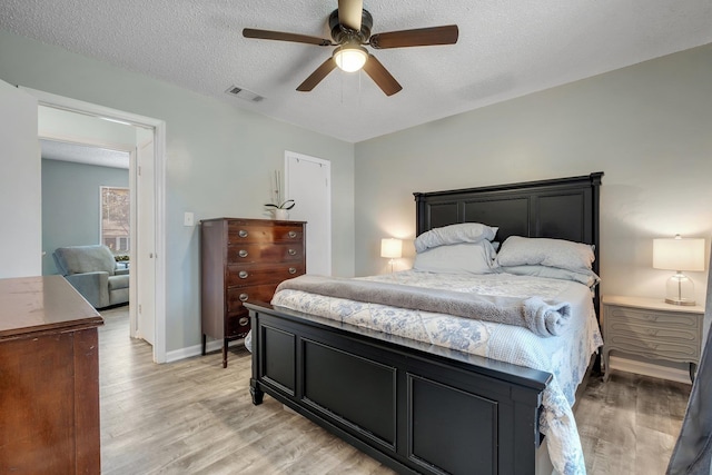 bedroom with a textured ceiling, light hardwood / wood-style flooring, and ceiling fan