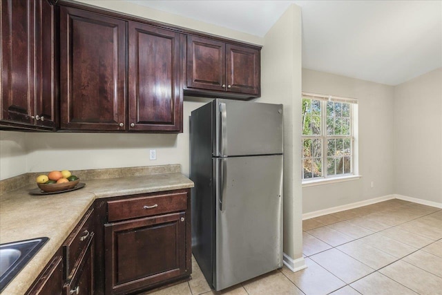 kitchen featuring light tile patterned floors, stainless steel refrigerator, and sink