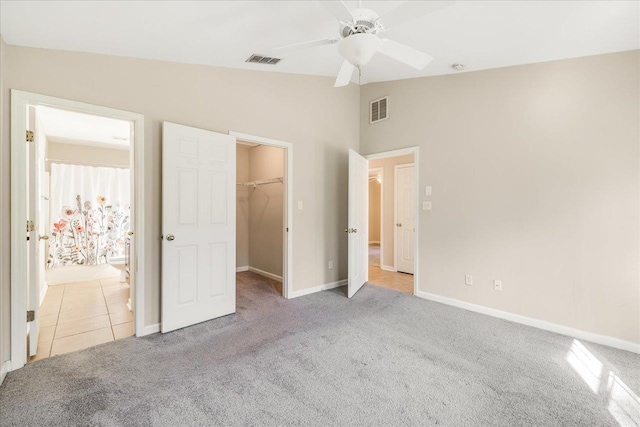 unfurnished bedroom with ceiling fan, a spacious closet, light colored carpet, lofted ceiling, and a closet