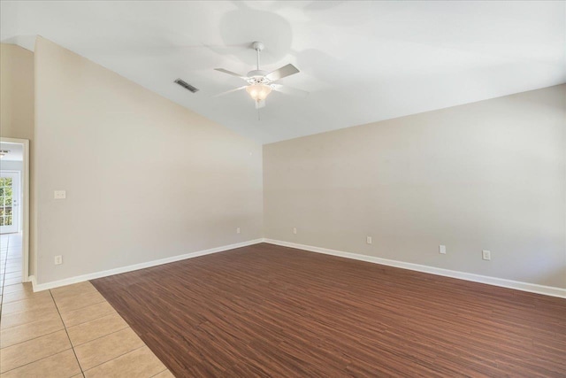 empty room with ceiling fan, light tile patterned floors, and vaulted ceiling