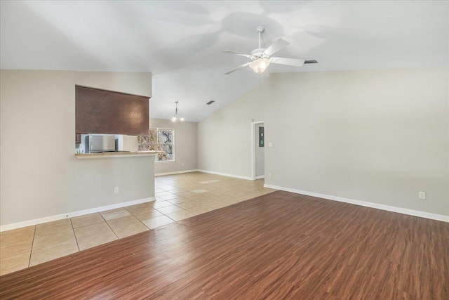 unfurnished living room featuring lofted ceiling, light tile patterned floors, and ceiling fan with notable chandelier