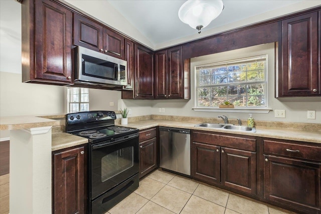 kitchen with sink, stainless steel appliances, plenty of natural light, vaulted ceiling, and light tile patterned floors