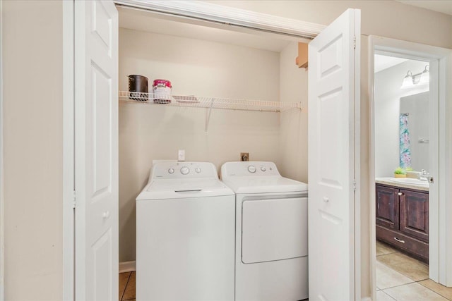 laundry room with light tile patterned flooring, independent washer and dryer, and sink