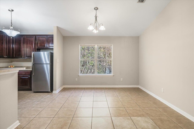 kitchen featuring pendant lighting, stainless steel fridge, light tile patterned floors, and a chandelier