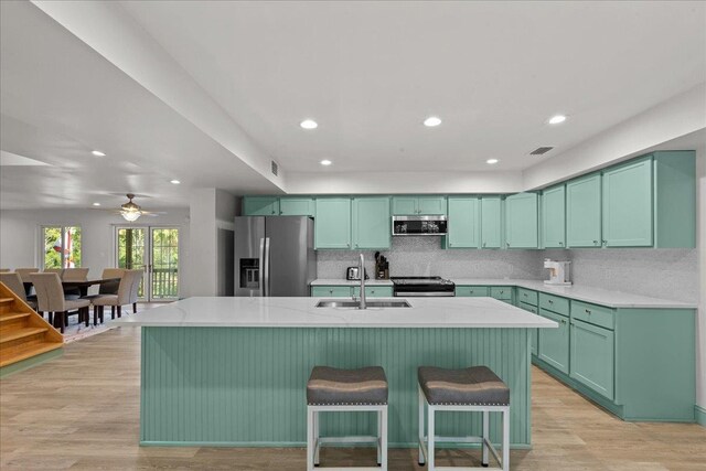 1334 Jr Howell Rd, Steinhatchee, FL 32359 - kitchen with stainless steel appliances, a kitchen island with sink, backsplash, recessed lighting, and a kitchen bar
