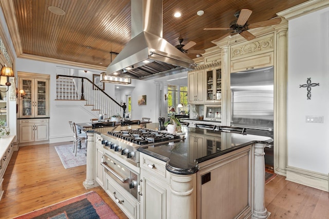 kitchen featuring island range hood, appliances with stainless steel finishes, a warming drawer, dark countertops, and cream cabinetry