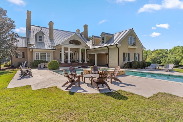 rear view of property featuring metal roof, a standing seam roof, a patio, and stucco siding