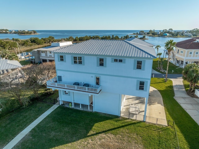 back of house featuring a lawn, a water view, and a balcony