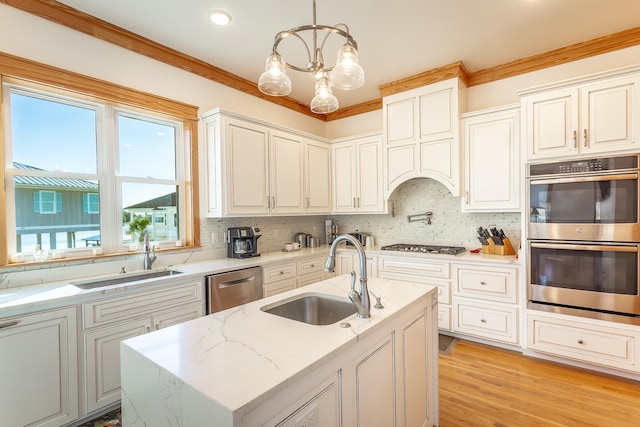 kitchen with pendant lighting, stainless steel appliances, a kitchen island with sink, and sink