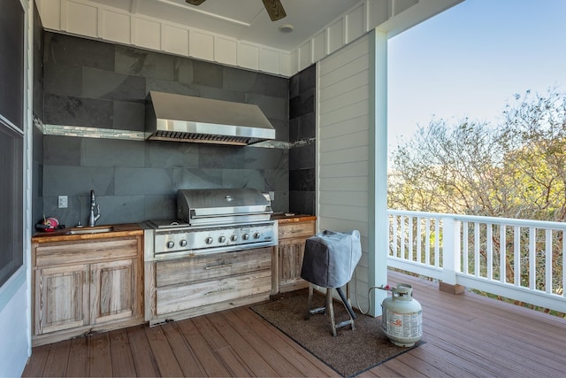 wooden terrace with area for grilling, ceiling fan, sink, and exterior kitchen