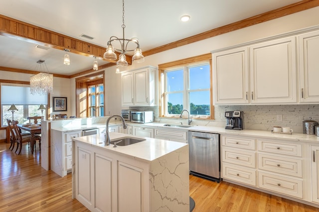 kitchen featuring dishwasher, an island with sink, hanging light fixtures, and sink