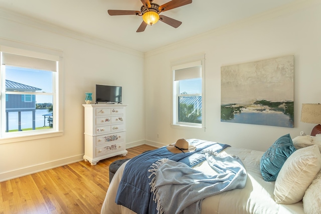 bedroom featuring multiple windows, ceiling fan, crown molding, and light hardwood / wood-style floors